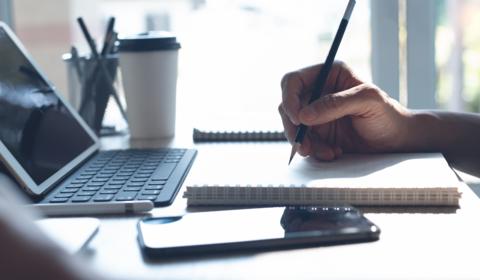 Person using a laptop and notebook to study