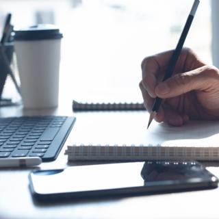 Person using a laptop and notebook to study