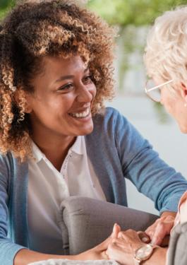A nurse and an elderly person in a care home holding hands