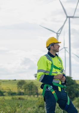 Two workers in hard hats are positioned before wind turbines, highlighting their commitment to sustainable energy solutions.