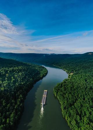 Boat traveling down river between green forests